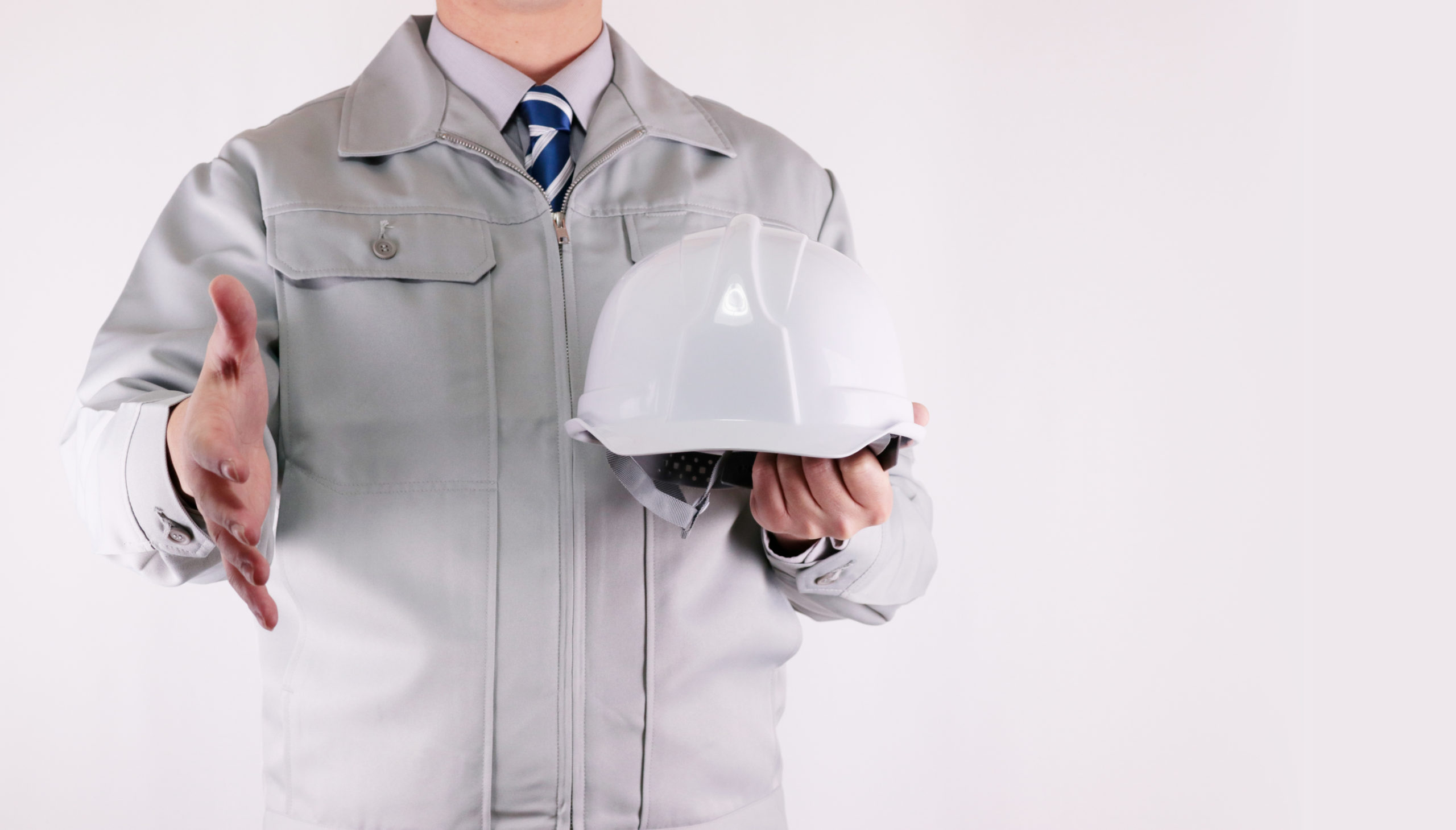 握手を求めるヘルメットを持った作業員